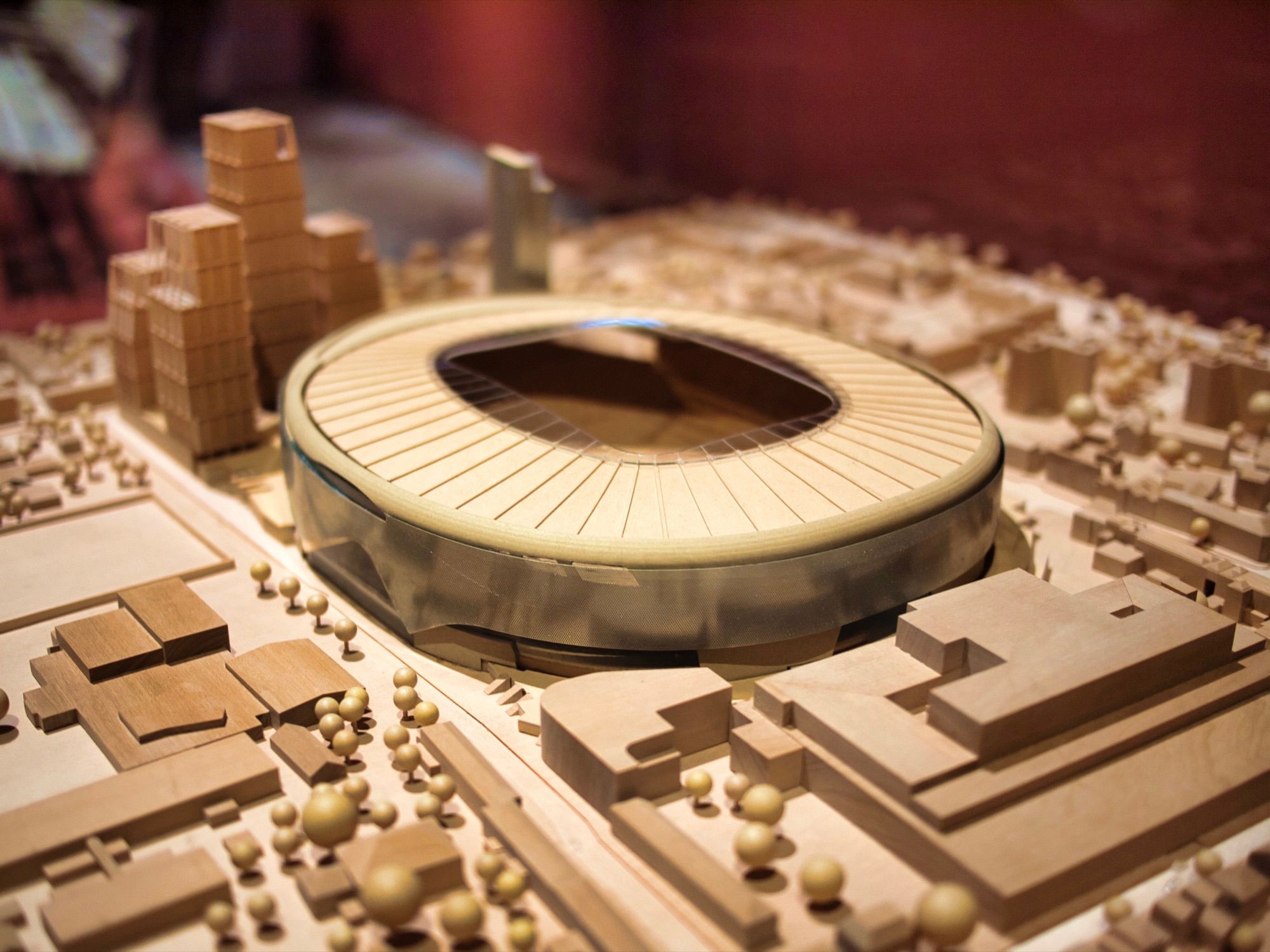 Maqueta de arquitectura en madera de un estadio y su entorno urbano, con edificios y árboles a escala