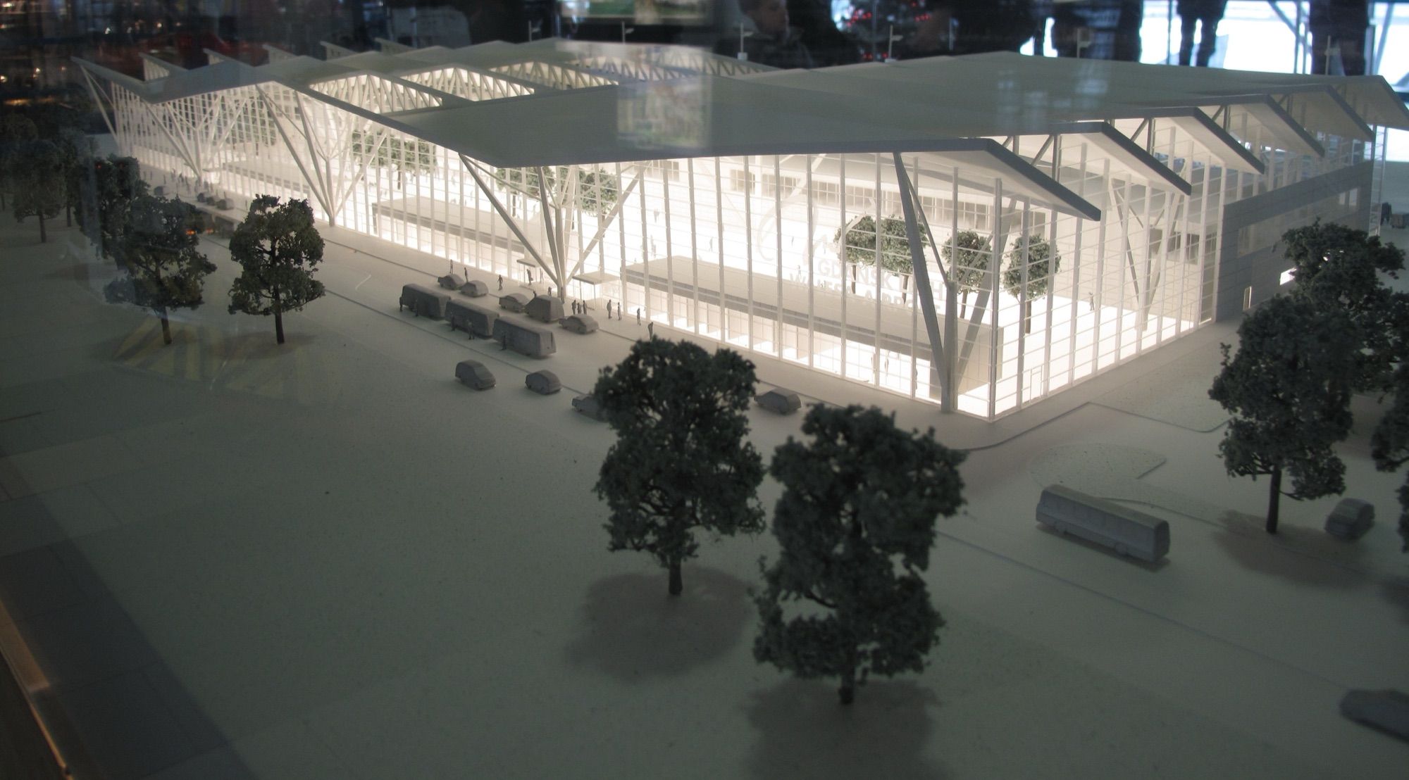 Maqueta iluminada de la terminal de un aeropuerto con árboles, autobuses y coches a escala