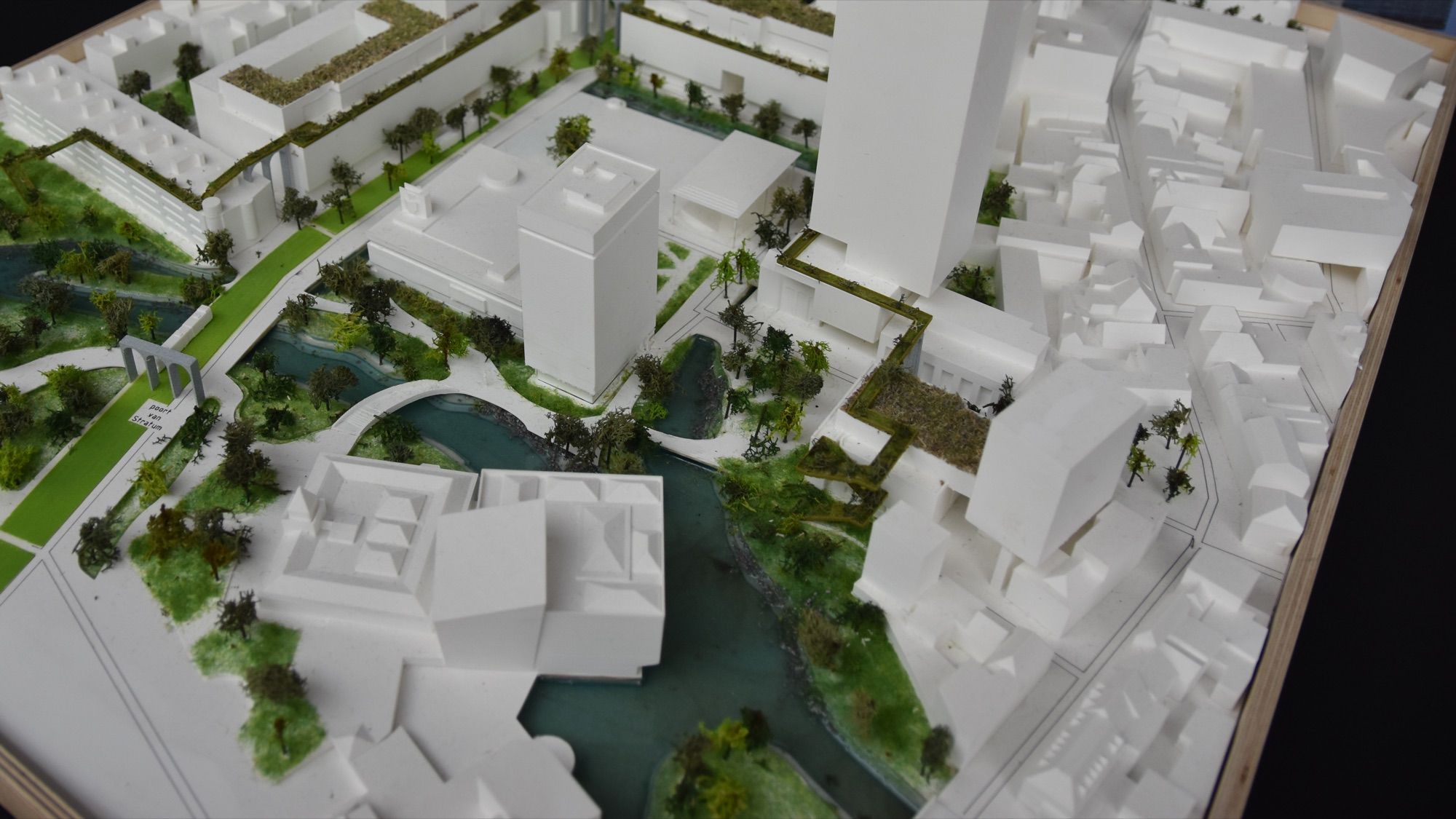 Maqueta de arquitectura blanca de un plan urbanístico con torres, zonas verdes, árboles y un canal